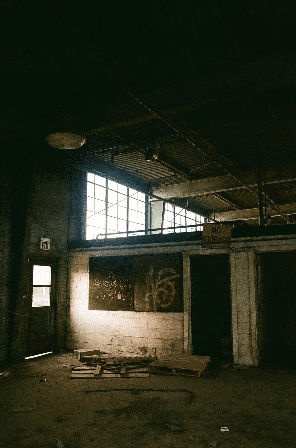Inside an abandoned industrial building, dark with light pouring in from windows