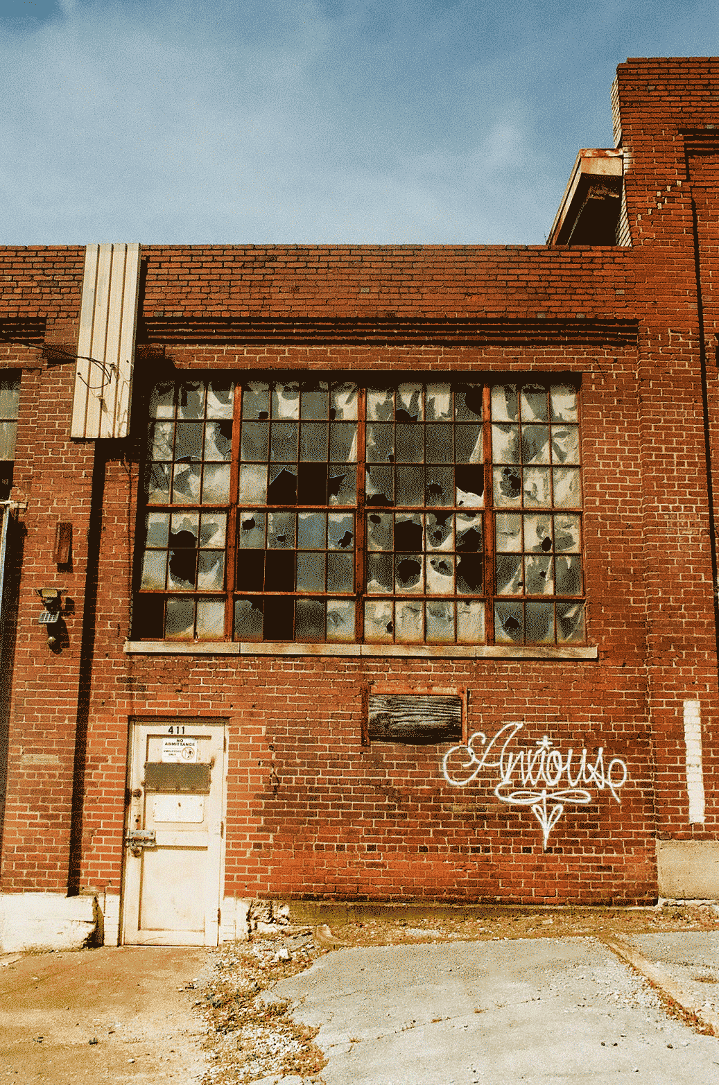 Abandoned factory with windows broken out, the word Anxious spray painted across it