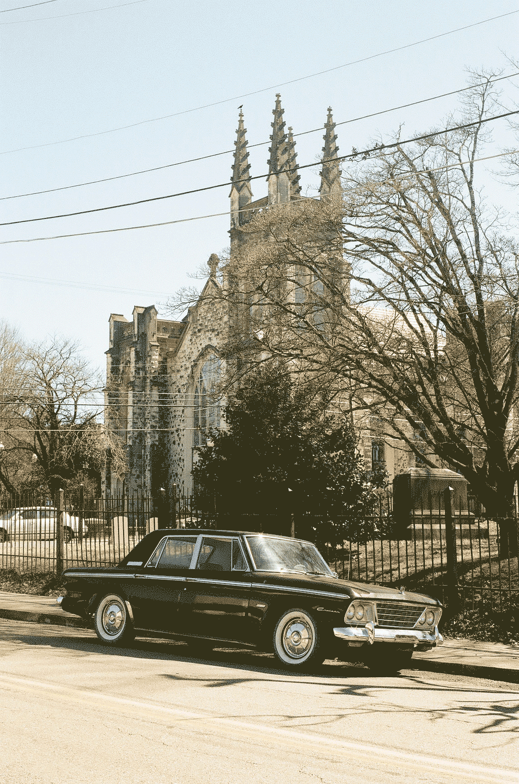 An old car sitting in front of a church with tall points
